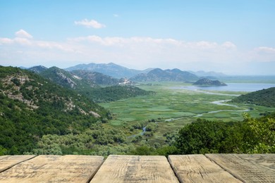 Empty wooden surface and view of beautiful mountains on sunny day