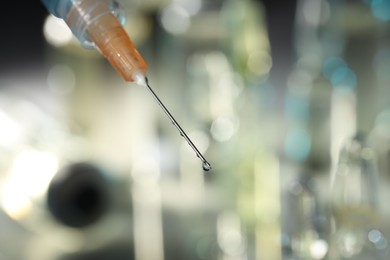 Syringe with medicine against blurred background, closeup. Space for text