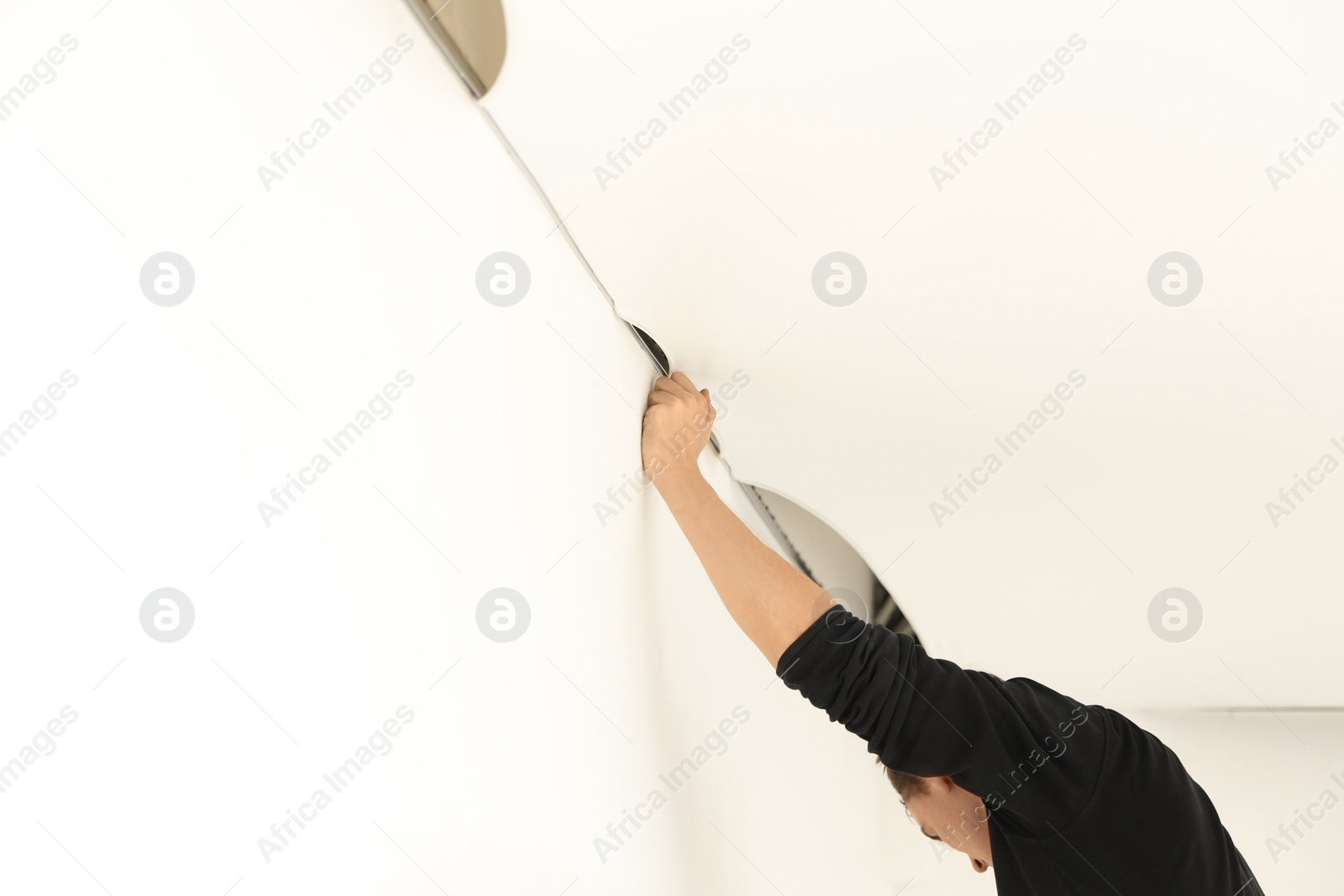 Photo of Repairman installing white stretch ceiling in room