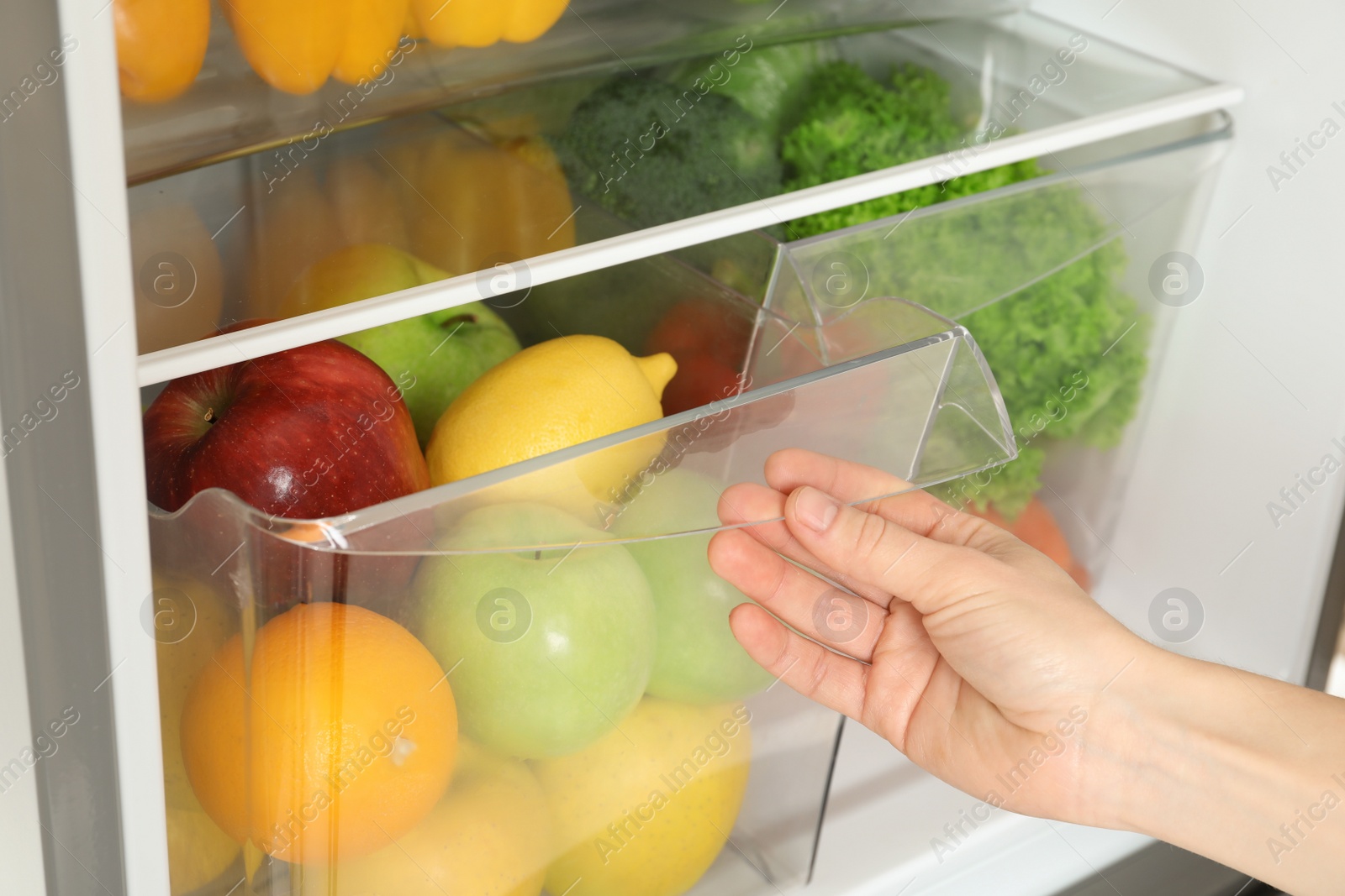 Photo of Woman opening refrigerator drawer with fresh fruits, closeup