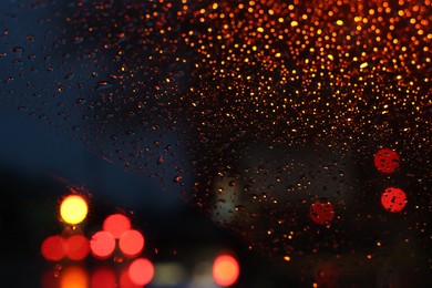 Photo of Blurred view of road through wet car window at night. Bokeh effect