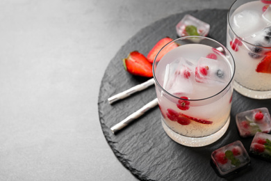 Photo of Glasses of refreshing drink with ice cubes and berries on grey table, closeup. Space for text