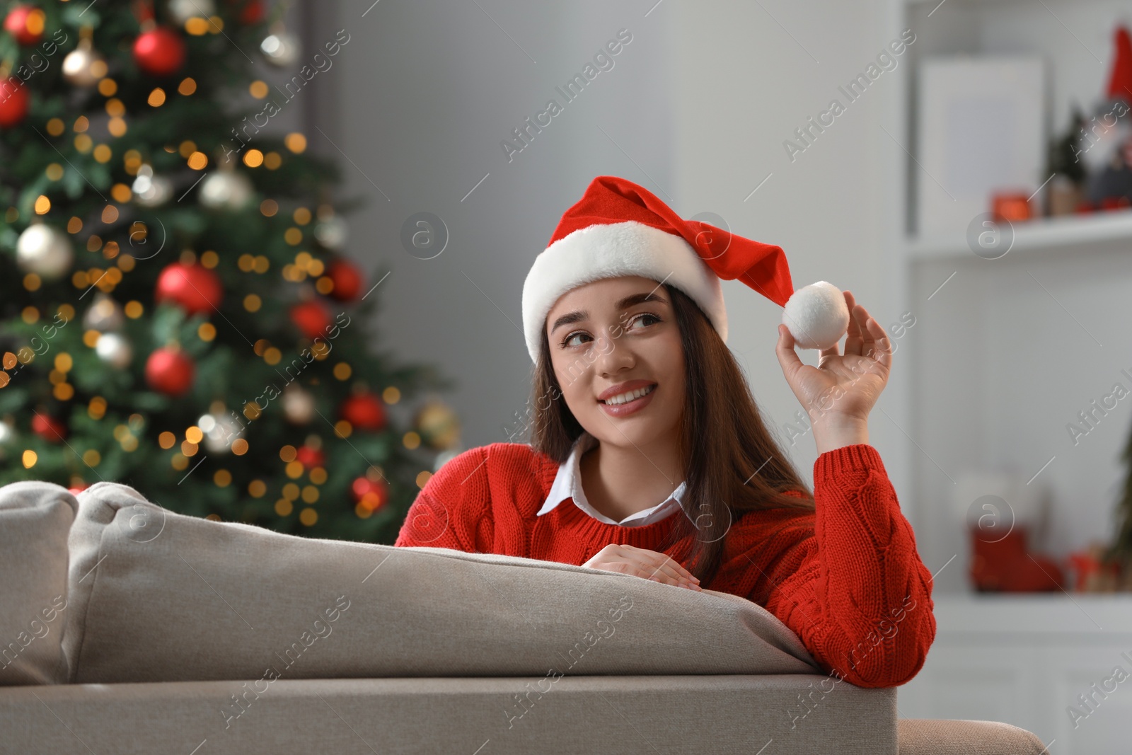 Photo of Smiling woman wearing red Christmas hat in cosy room