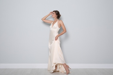 Photo of Young bride wearing beautiful wedding dress near light grey wall