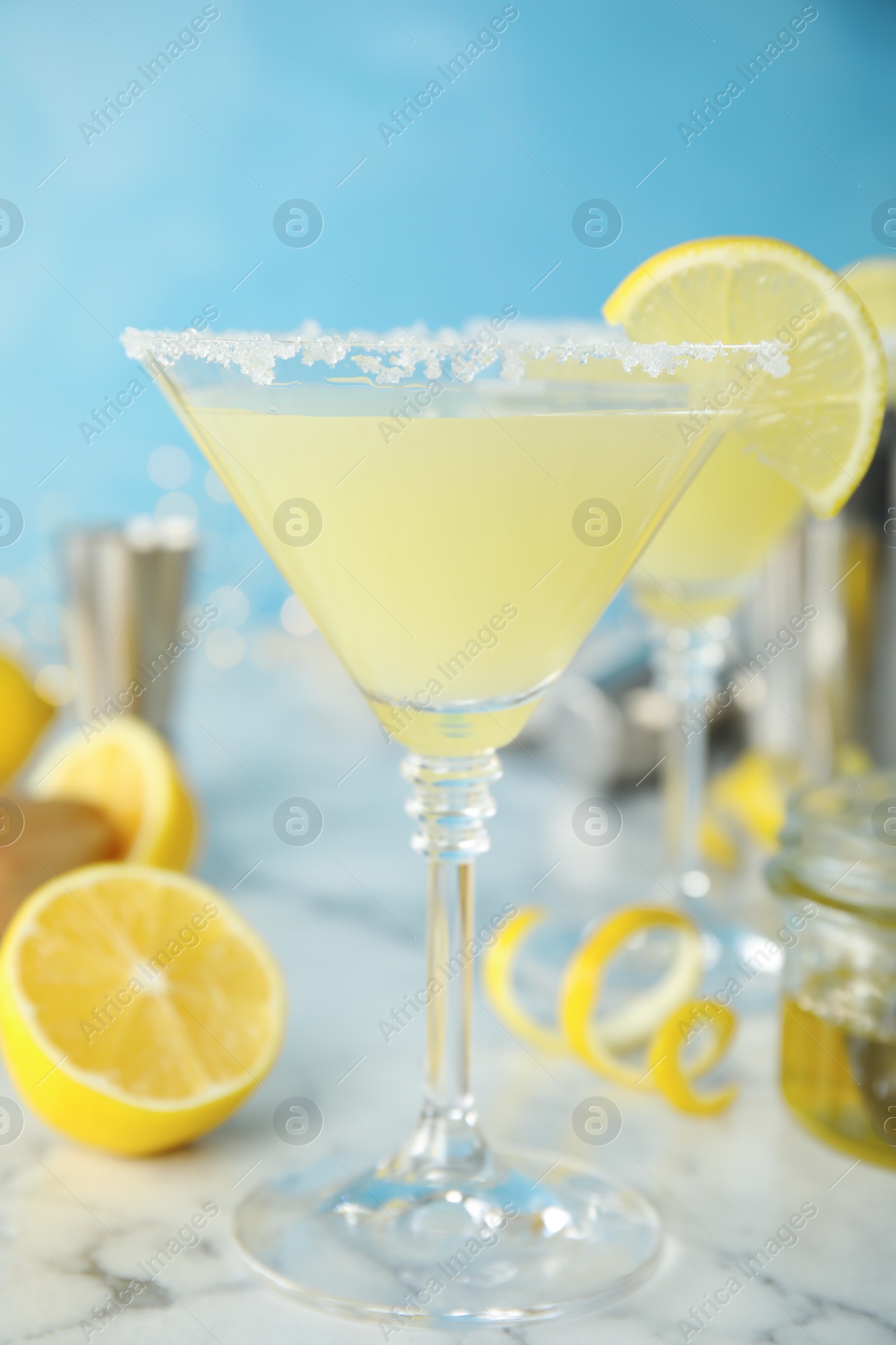 Photo of Delicious bee's knees cocktail and ingredients on white marble table against light blue background