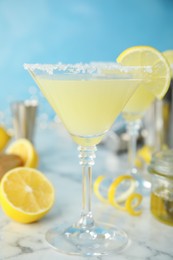 Photo of Delicious bee's knees cocktail and ingredients on white marble table against light blue background