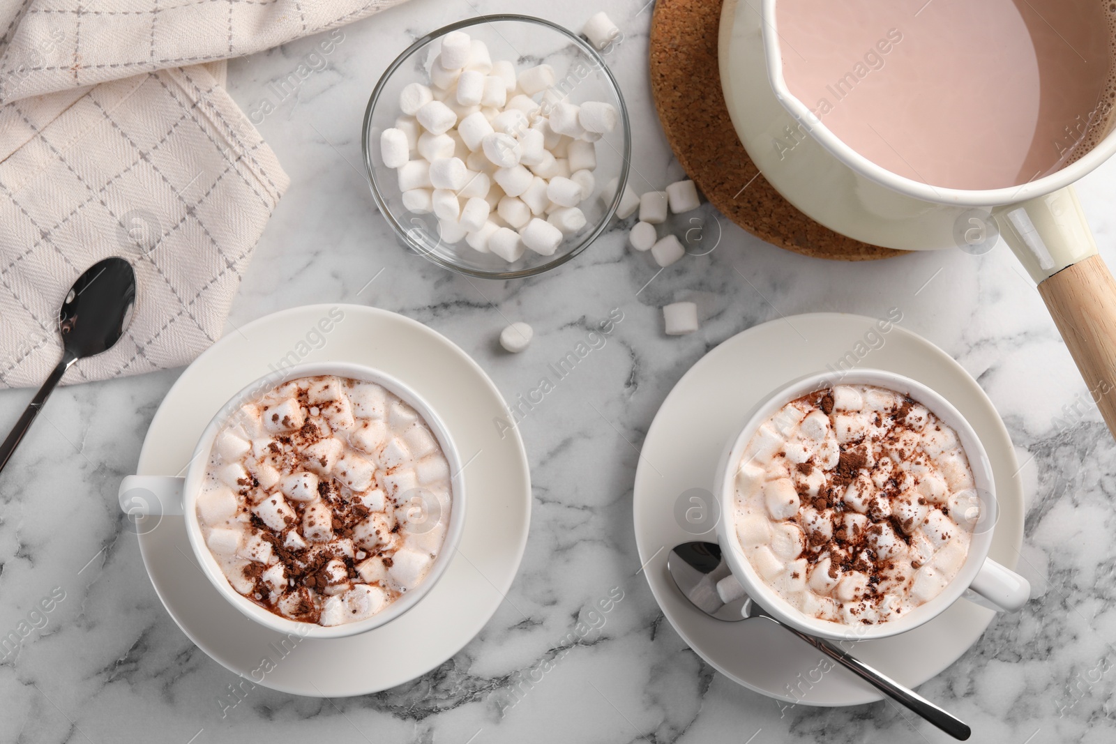 Photo of Aromatic hot chocolate with marshmallows and cocoa powder served on white marble table, flat lay