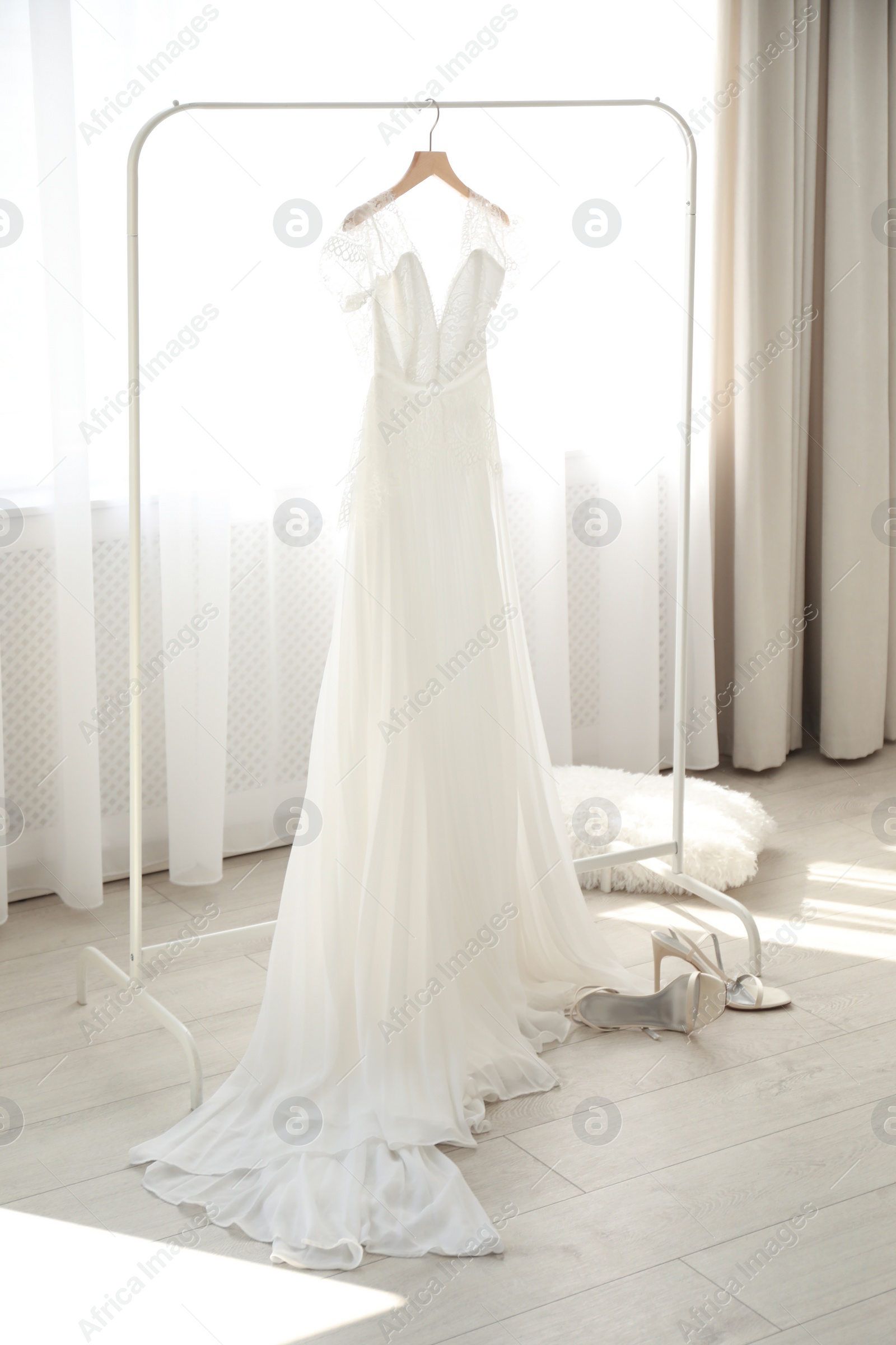 Photo of Beautiful wedding dress hanging on clothing rack in room