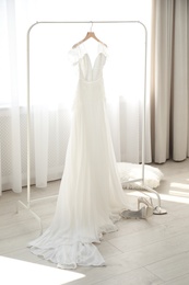 Photo of Beautiful wedding dress hanging on clothing rack in room