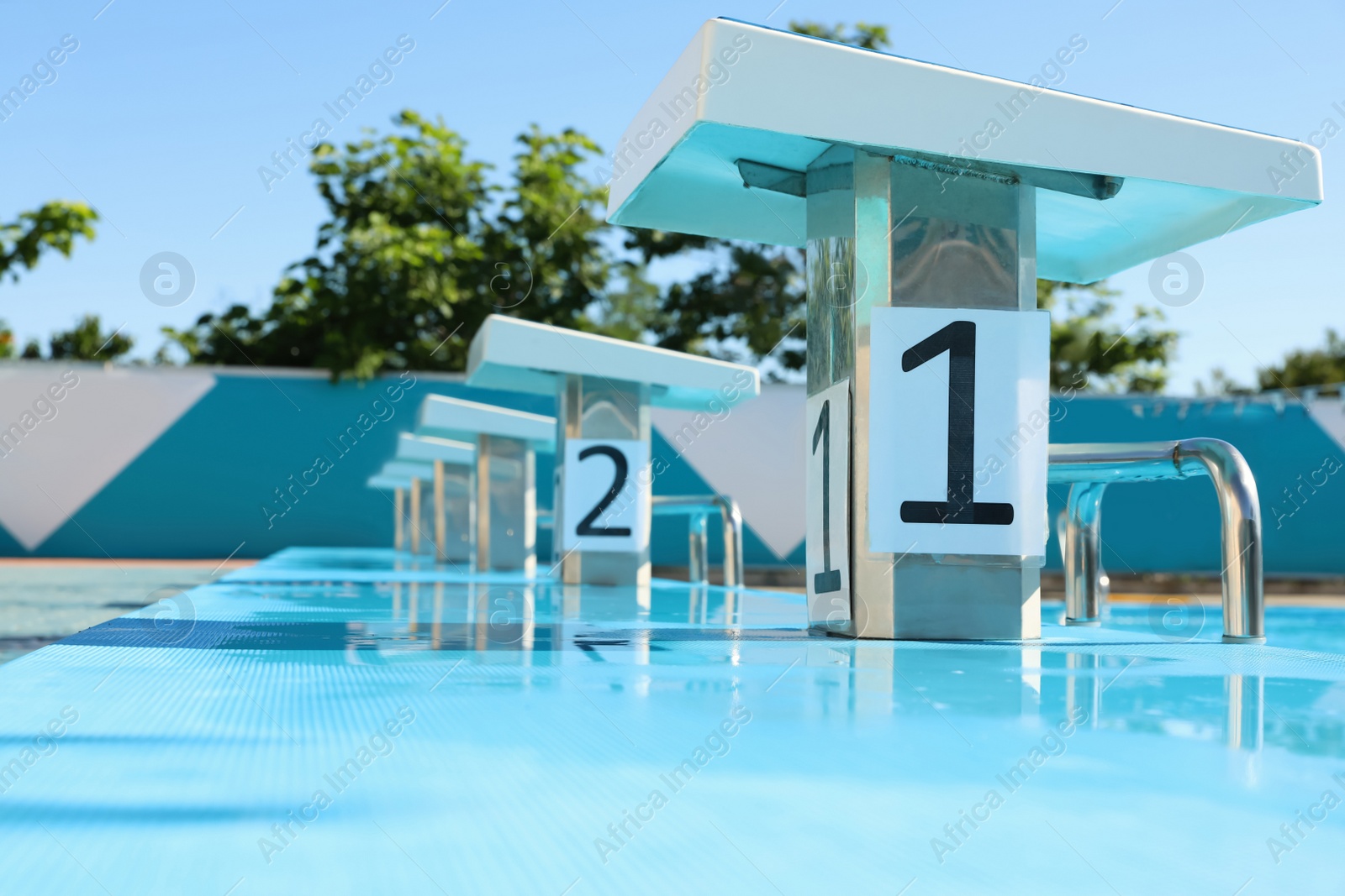 Photo of Starting platforms near outdoor swimming pool on sunny day