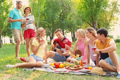 Happy friends having picnic in park on sunny day