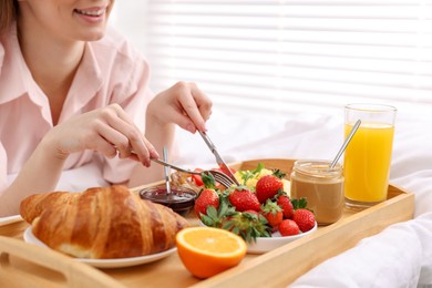 Photo of Smiling woman having tasty breakfast on bed, closeup