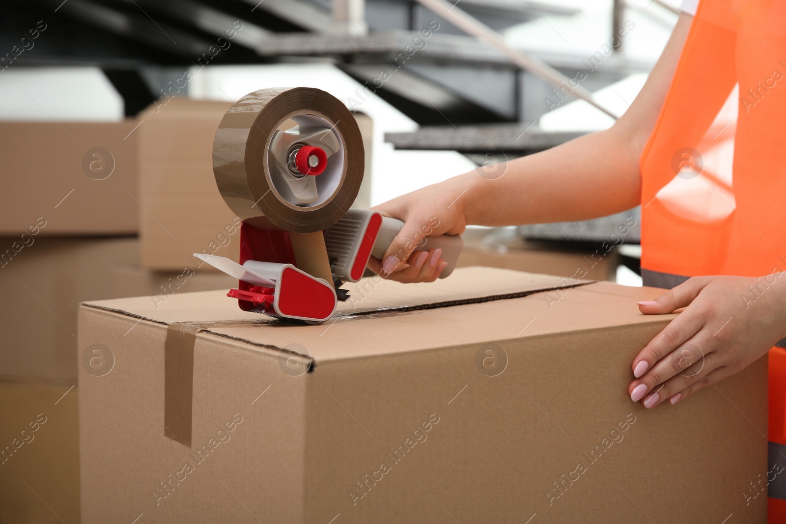 Photo of Worker taping cardboard box indoors, closeup view