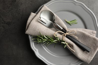 Stylish setting with cutlery and napkin on black table, top view. Space for text