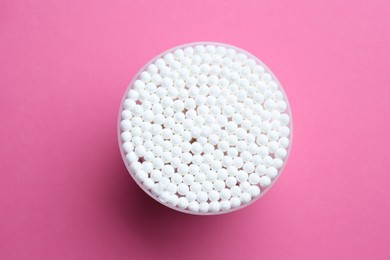 Photo of Many cotton buds in container on pink background, top view