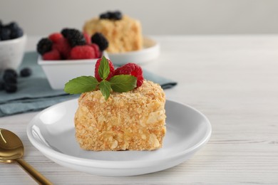 Photo of Piece of Napoleon cake with raspberries and spoon on wooden table, closeup