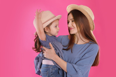 Photo of Young mother and little daughter with hats on pink background