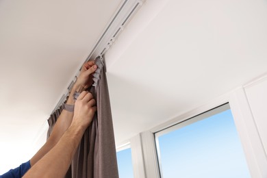 Photo of Worker hanging window curtain indoors, low angle view. Space for text
