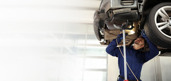 Image of Technician checking modern car at automobile repair shop, space for text. Banner design