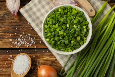 Photo of Chopped green onion in bowl on wooden table, flat lay