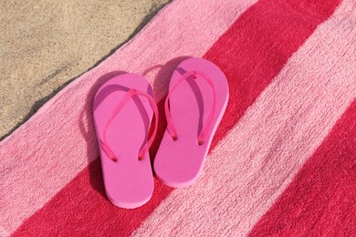 Photo of Beach towel and stylish slippers on sand, above view