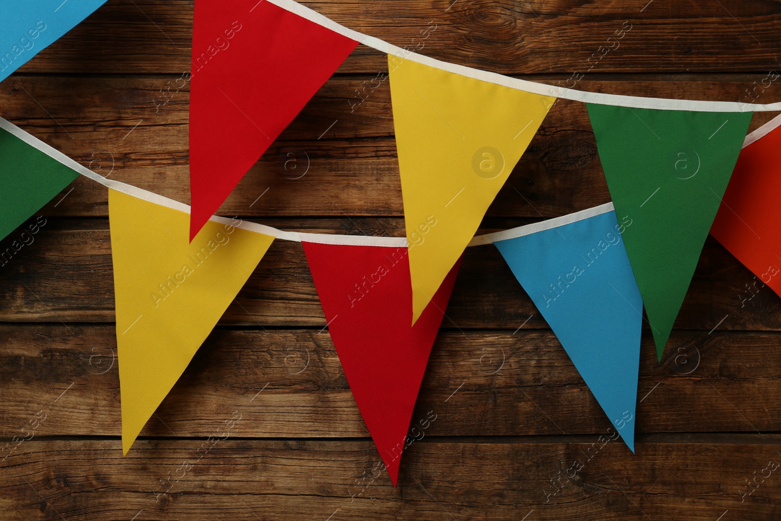 Photo of Buntings with colorful triangular flags on wooden background