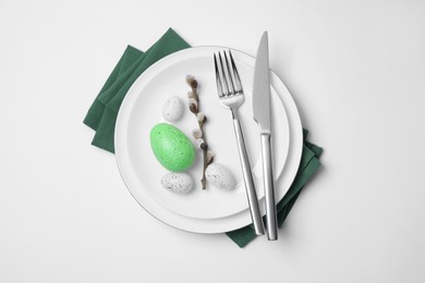 Photo of Festive table setting with willow twig and painted eggs on white background, top view. Easter celebration