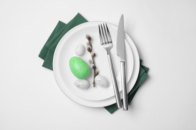 Festive table setting with willow twig and painted eggs on white background, top view. Easter celebration