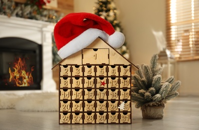 Wooden house shaped Advent calendar in room decorated for New Year