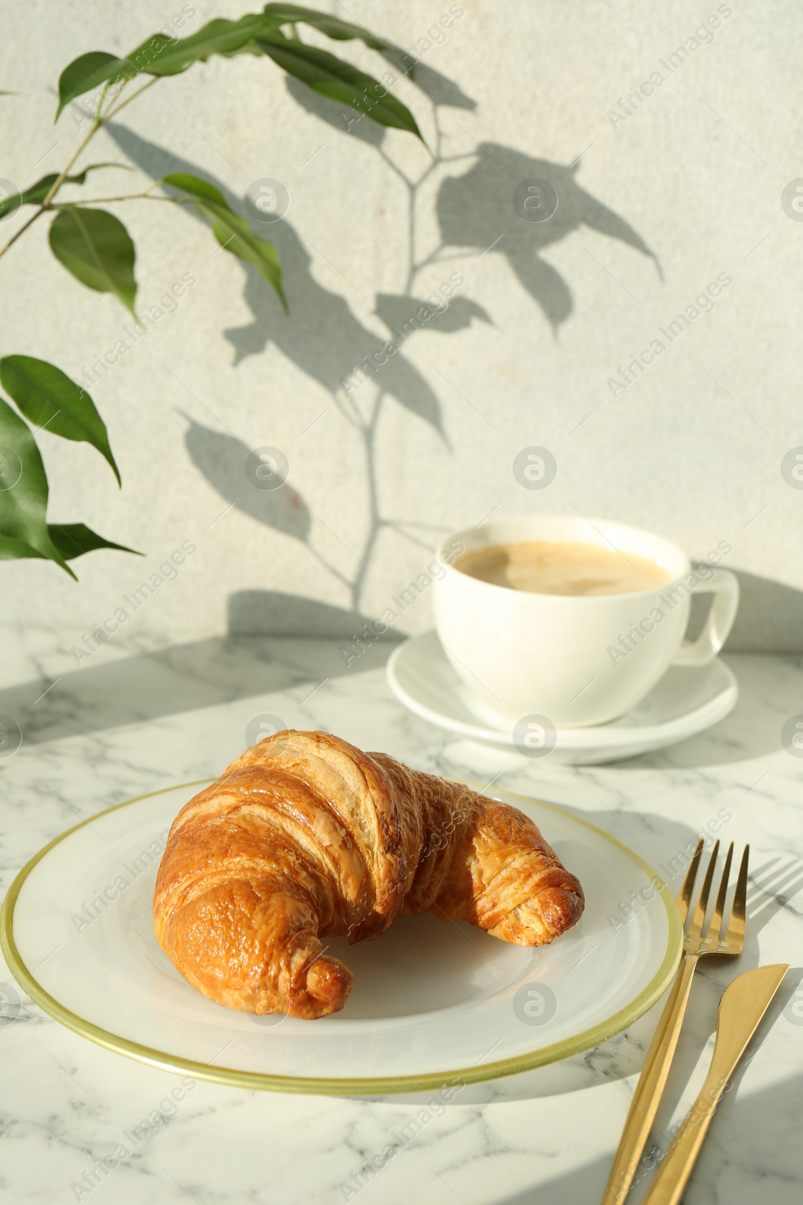 Photo of Delicious fresh croissant served with coffee on white marble table