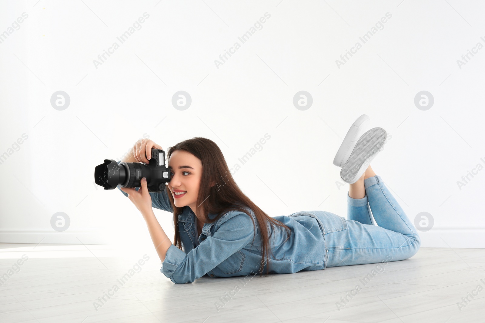 Photo of Female photographer with camera lying on floor indoors