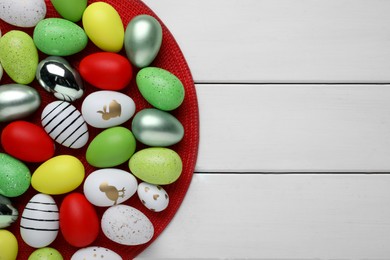 Photo of Many beautifully decorated Easter eggs on white wooden table, top view. Space for text