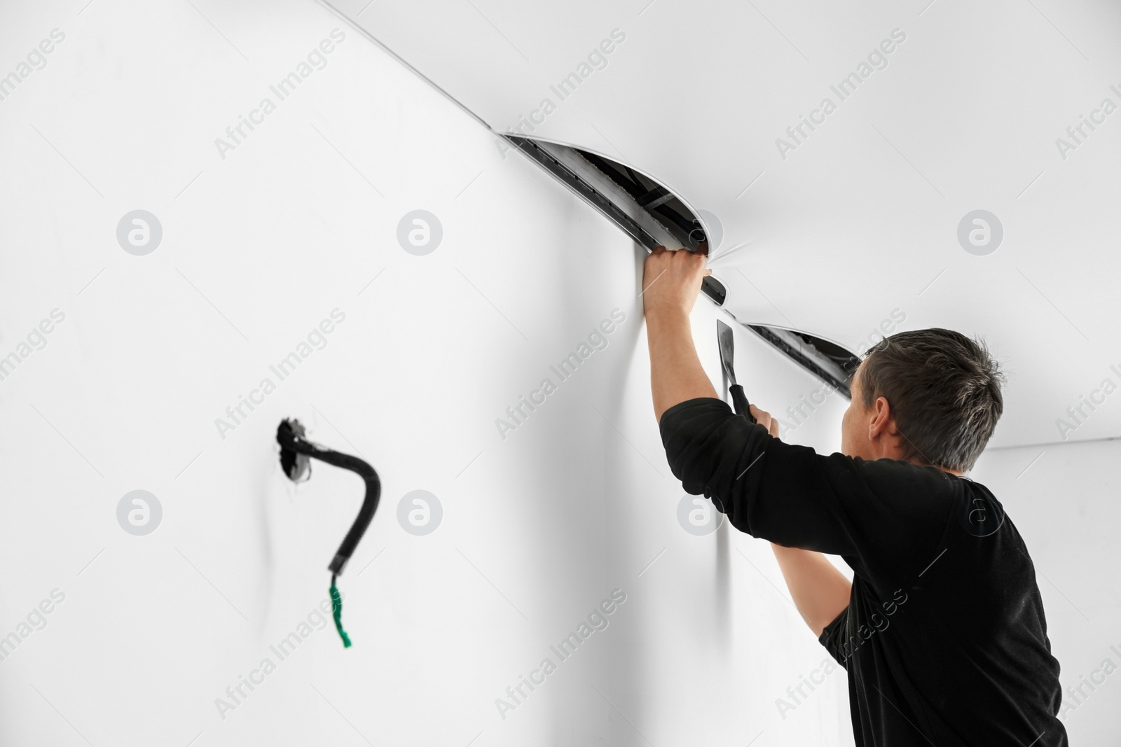 Photo of Repairman installing white stretch ceiling in room