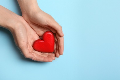 Woman holding heart on blue background, top view with space for text. Donation concept