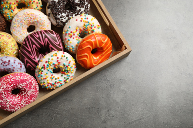 Photo of Top view of yummy donuts with sprinkles in box, space for text