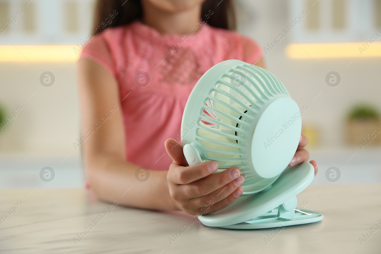 Photo of Little girl with portable fan at home, closeup. Summer heat