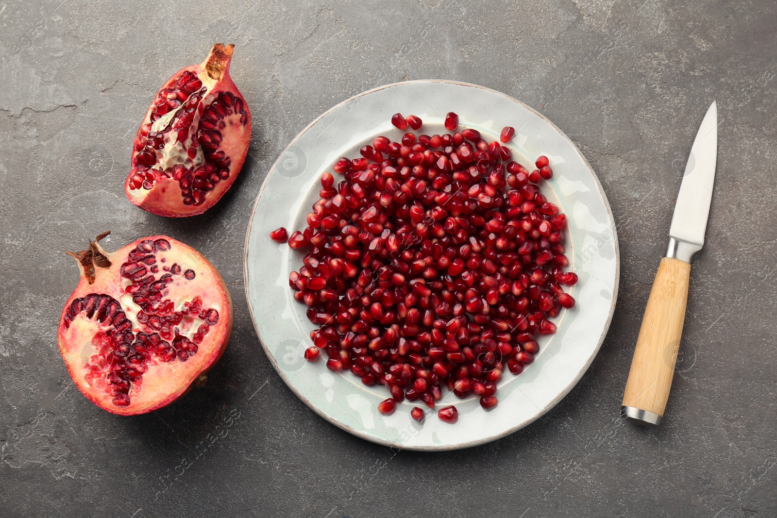 Photo of Tasty ripe pomegranate and grains on grey table, flat lay