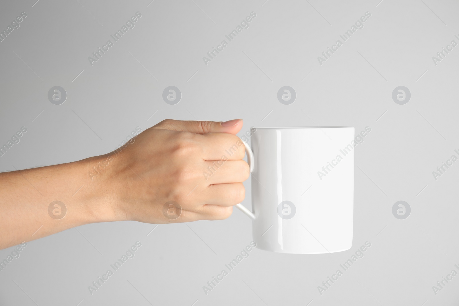 Photo of Woman holding ceramic cup on light background. Mock up for design