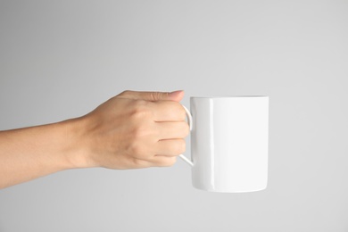 Photo of Woman holding ceramic cup on light background. Mock up for design