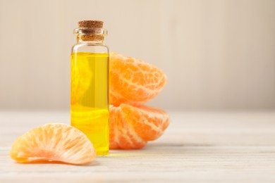 Bottle of tangerine essential oil and fresh fruit on white wooden table, closeup. Space for text