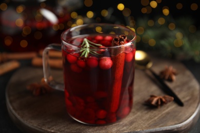 Photo of Tasty hot cranberry tea with rosemary and cinnamon on wooden table, closeup