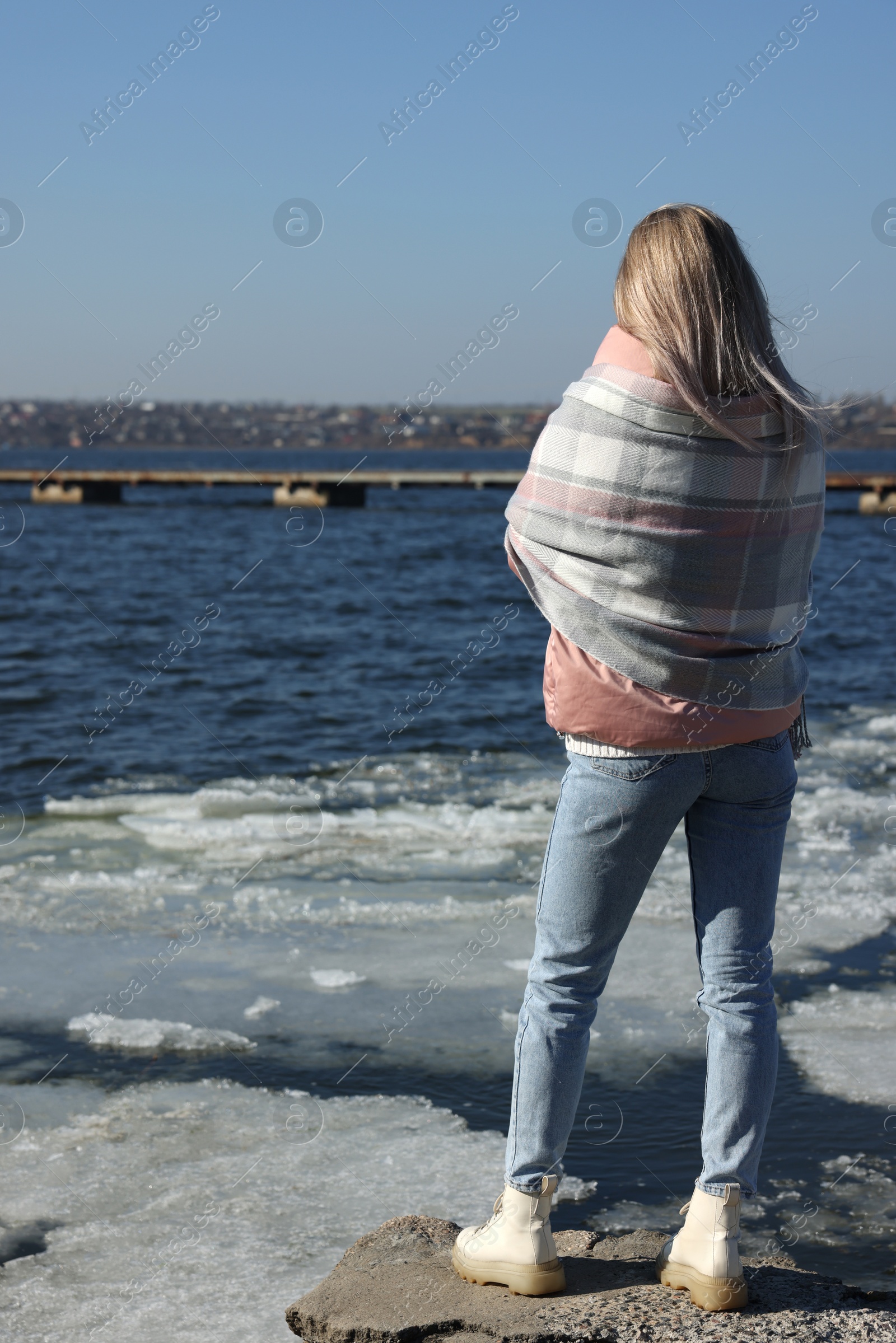 Photo of Lonely woman near river on sunny day, back view