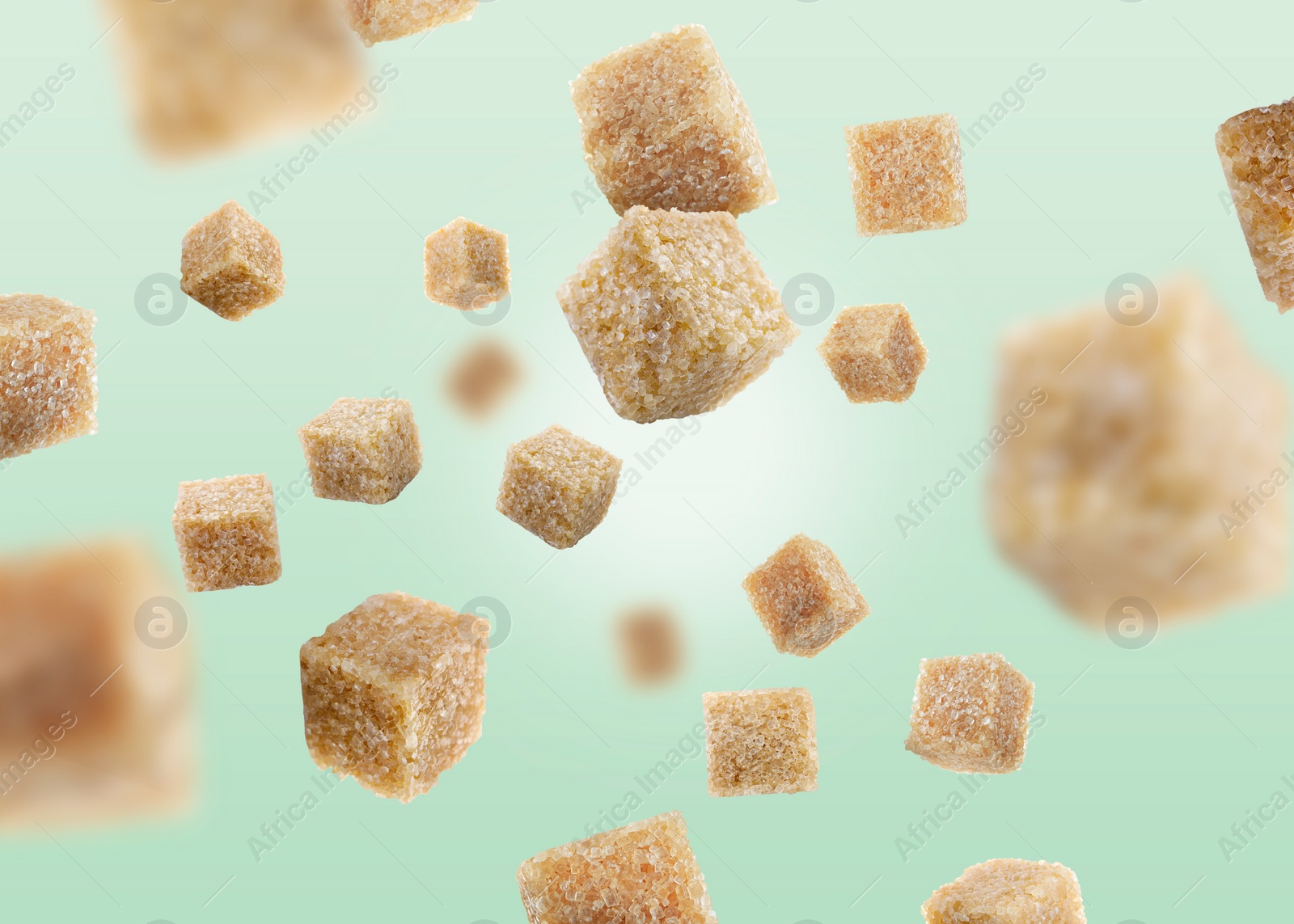 Image of Brown cane sugar cubes falling on turquoise gradient background