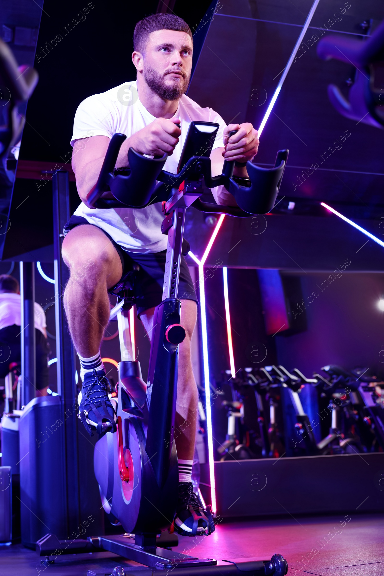 Photo of Young man training on exercise bike in fitness club