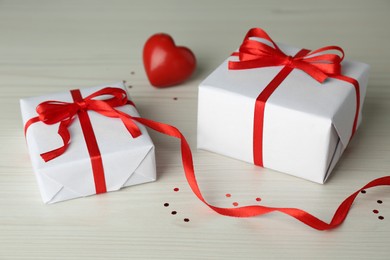 Photo of Beautiful gift boxes with red heart on wooden table
