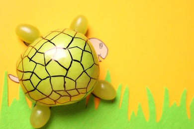 Photo of Funny turtle made of grapes on color background, top view. Space for text