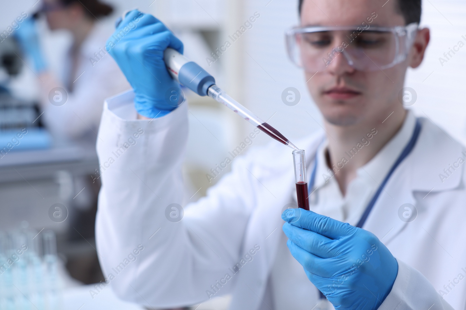 Photo of Scientist dripping sample into test tube in laboratory, selective focus