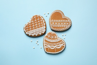 Photo of Tasty heart shaped gingerbread cookies on light blue background, flat lay
