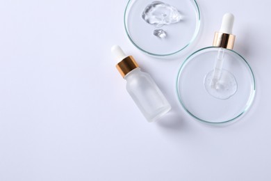 Photo of Petri dishes with samples of cosmetic serums, pipette and bottle on white background, flat lay. Space for text