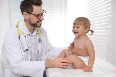 Photo of Pediatrician examining cute little baby in clinic